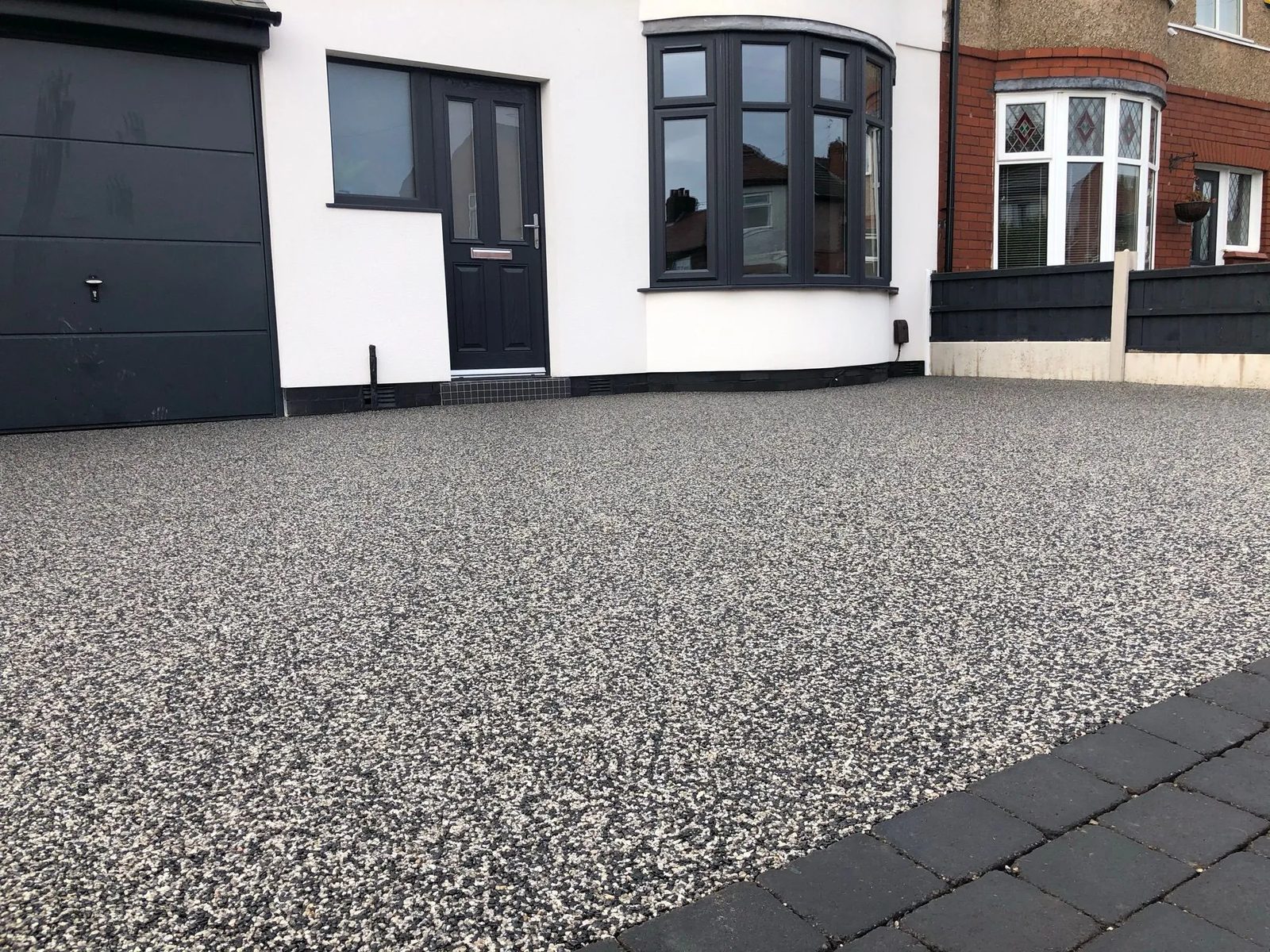 Silver grey resin bound driveway in front of a white rendered house